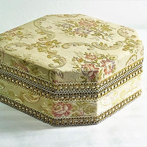 May include: A hexagonal shaped decorative box with a floral pattern and gold trim.