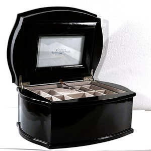 May include: Black wooden jewelry box with a hinged lid and a clear picture frame on the top. The frame has the text "Things Remembered" printed on it. The box has a velvet interior with multiple compartments.