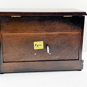 May include: A dark brown wooden music box with a hinged lid and a gold label that reads "Quality Products Jay Instruments UK".