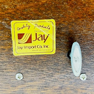 May include: A yellow label with the text "Quality Products Designed for Jay Jay Import Co. Inc. Made in Taiwan" on a wooden surface. The label has a stylized Jay logo with a wavy line design.