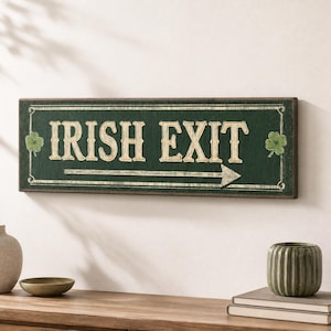 May include: A rectangular dark green wooden sign featuring the text IRISH EXIT in large, light-colored serif letters. The sign includes a horizontal arrow pointing to the right and a small green shamrock illustration on both the left and right sides.