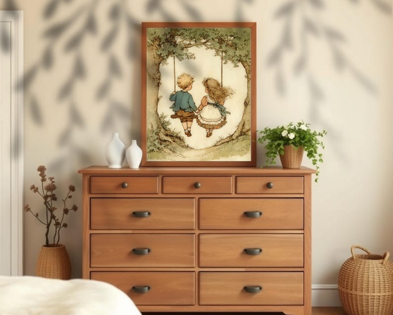 May include: A framed print depicts a boy and girl on a swing under a tree. The artwork features soft colors and a vintage style. The frame is a warm brown, and the print is displayed on a wooden dresser with dark hardware. Decorative vases and a potted plant are also on the dresser.