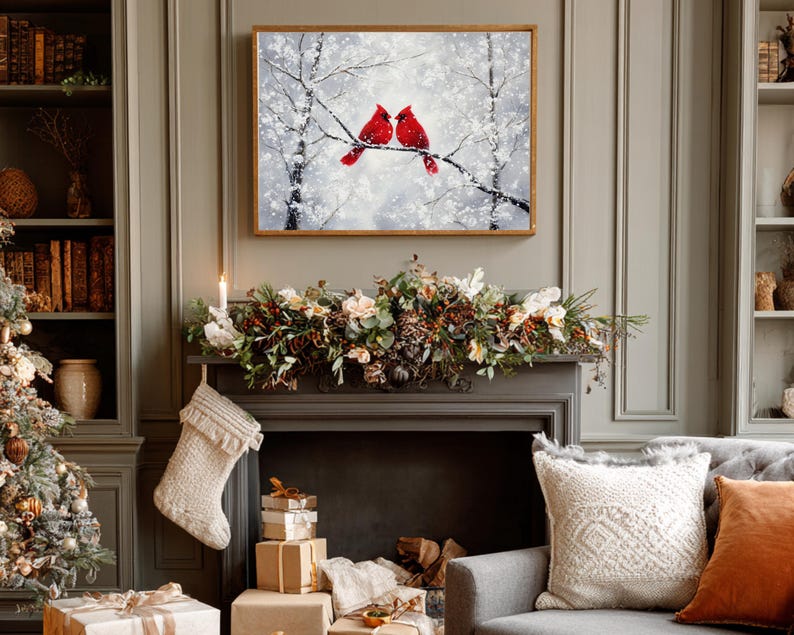 May include: A framed painting depicts two red cardinals perched on a snow-covered branch. The artwork hangs above a fireplace decorated with a garland of flowers and greenery. A Christmas stocking hangs from the mantel.