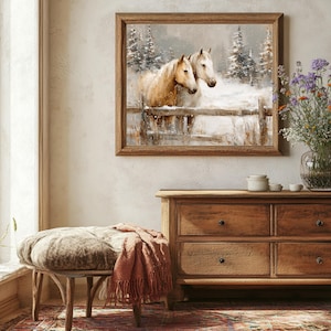 May include: A framed artwork depicts two horses in a snowy landscape, with a wooden fence and evergreen trees. The artwork hangs above a wooden dresser with four drawers. A bench with a patterned cushion and a terracotta throw blanket sits in front of the dresser.