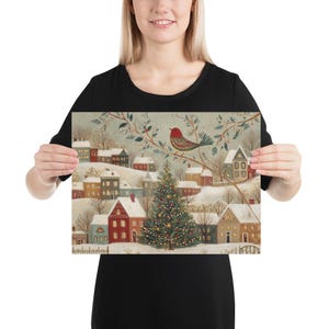 May include: A rectangular art print featuring a winter village scene with snow-covered houses, a central decorated Christmas tree, and a red bird perched on a branch. The illustration uses a muted colour palette with soft white, red, and green tones.