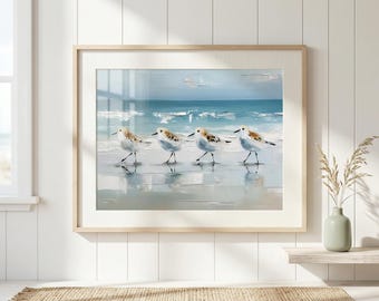 May include: Framed art print featuring four shorebirds walking along a beach. The artwork depicts the birds in a row, with a light blue ocean and sky in the background. The print is in a light wood frame, adding a touch of coastal decor.