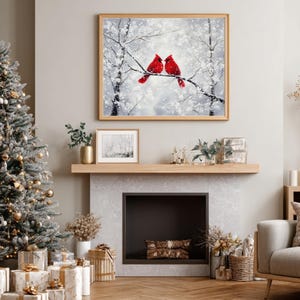 May include: A cozy living room scene with a decorated Christmas tree, wrapped gifts, and a framed painting of two red cardinals perched on a snowy branch. The room features a fireplace and neutral-toned furniture.
