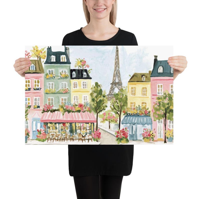 May include: A colorful print of a Parisian street scene featuring buildings in shades of pink, yellow, and green, adorned with flowers and awnings. The Eiffel Tower is visible in the background, with trees lining the street.