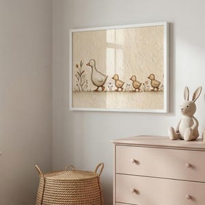 May include: A framed print featuring a mother duck and her ducklings walking in a row. The artwork is in soft, muted tones of beige, gray, and yellow. The print is displayed above a pink dresser, with a bunny figurine and a woven basket.