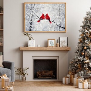 May include: A framed winter landscape painting featuring two vibrant red cardinals perched on a snow-covered branch. The artwork hangs above a fireplace, complemented by a decorated Christmas tree and wrapped gifts, creating a festive holiday scene.