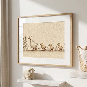 May include: A framed print featuring a mother duck and her three ducklings walking in a line. The artwork is in soft, neutral tones, with a beige background and a light wooden frame. The illustration has a whimsical, gentle feel.