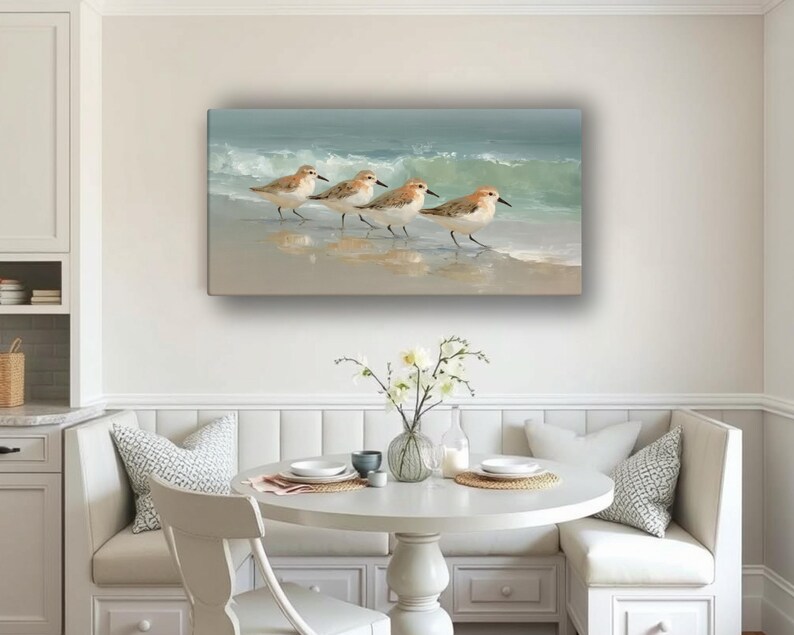 May include: A rectangular canvas print depicts four shorebirds walking along a sandy beach with gentle waves in the background. The birds have brown and white feathers, and the ocean is a mix of blue and green.