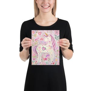 May include: A whimsical print featuring a unicorn with a golden horn and flowing pink mane and tail, surrounded by colorful flowers and hearts. The artwork has a soft, pastel color palette, creating a dreamy and enchanting scene.