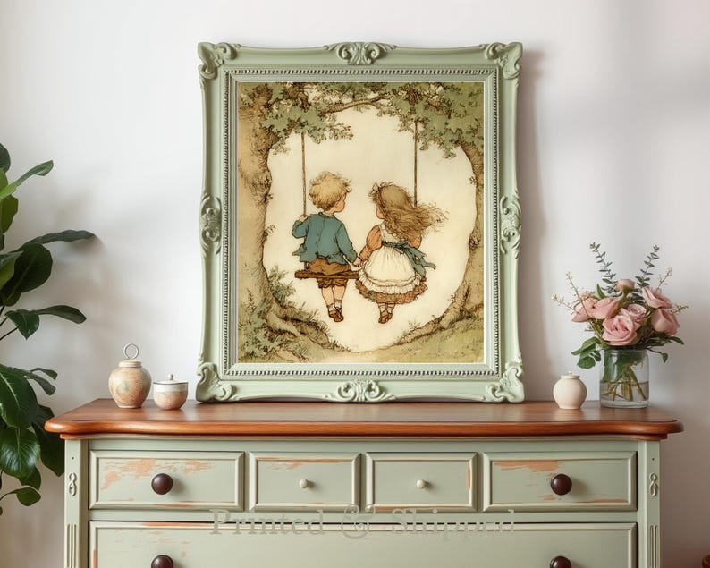May include: A framed print depicts two children on a swing, set against a backdrop of a tree. The artwork features soft colors and a vintage aesthetic. The frame is a light green with ornate detailing. The print is displayed on a light green dresser.