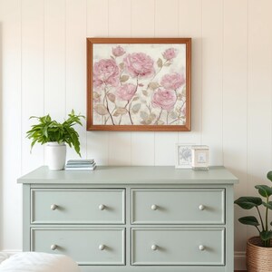 May include: A framed floral print featuring pink roses hangs above a light green dresser. The dresser has six drawers with round, light-colored knobs. A potted plant and decorative items sit on top of the dresser.