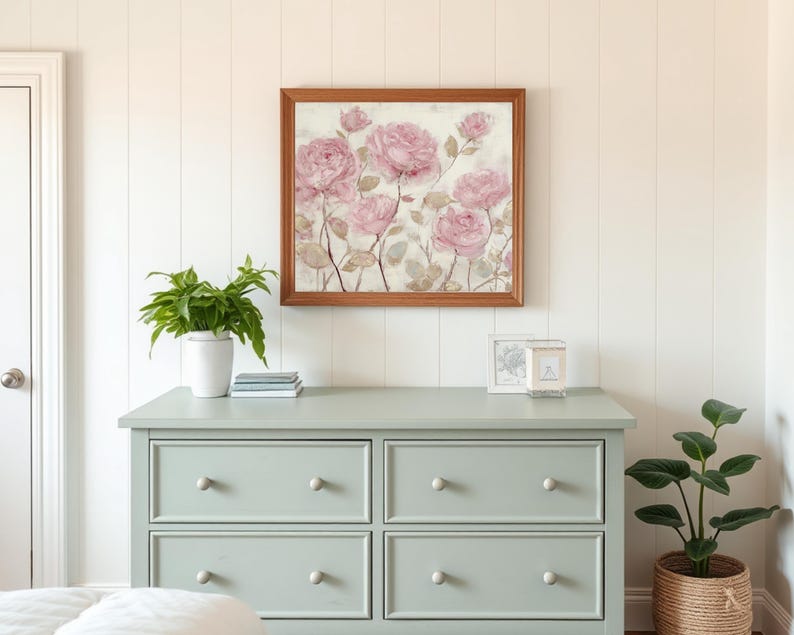 May include: A framed floral print featuring pink roses hangs above a light green dresser. The dresser has six drawers with round, light-colored knobs. A potted plant and decorative items sit on top of the dresser.