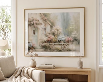 Può includere: Una stampa artistica da parete incorniciata che presenta un'illustrazione in stile acquerello di un cottage con una porta azzurra, circondato da fiori rosa e bianchi, e un carretto di legno pieno di composizioni floreali colorate.
