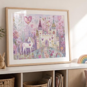 May include: A framed art print featuring a white unicorn standing in a garden with a castle in the background. The illustration includes pink hearts, colourful flowers, and trees in shades of purple, pink, and green, all enclosed in a light wood frame.