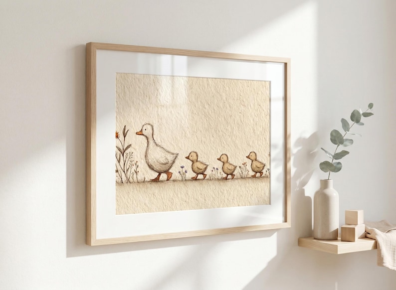 May include: Framed art print featuring a mother duck and her three ducklings walking in a line. The illustration is in soft, muted tones of beige, brown, and green, creating a gentle, nature-inspired scene. The artwork is framed in a light wood frame.