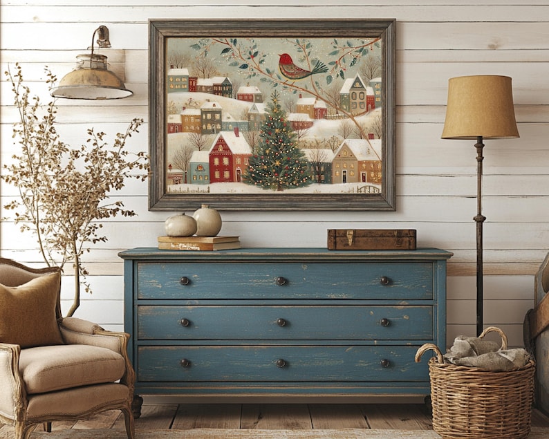 May include: A framed wall art print depicting a snowy winter village scene with colourful houses, a central decorated Christmas tree, and a red bird perched on a branch, all enclosed within a dark wooden frame with a textured finish.