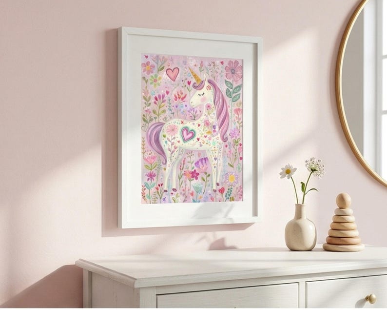 May include: A framed watercolor print of a unicorn surrounded by flowers in shades of pink, purple, and green. The unicorn has a golden horn and a heart-shaped design on its body. The artwork is displayed on a white dresser.