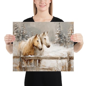 May include: A print featuring two horses in a snowy landscape. The horses, one light brown and one white, stand near a wooden fence. Snow-covered evergreen trees are in the background, creating a winter scene.