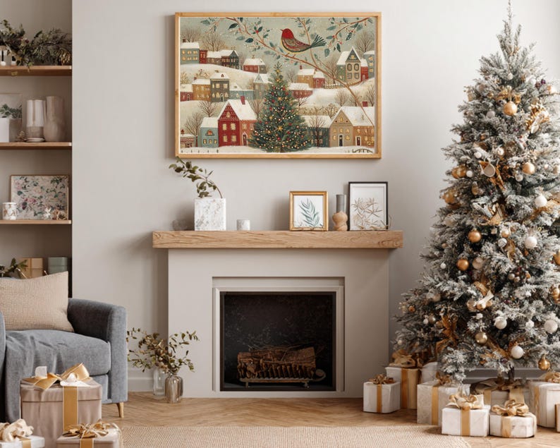 May include: A framed horizontal wall art print depicting a snowy winter village scene with colourful houses, a central decorated Christmas tree, and a red bird perched on a branch, displayed above a fireplace mantel in a living room setting.