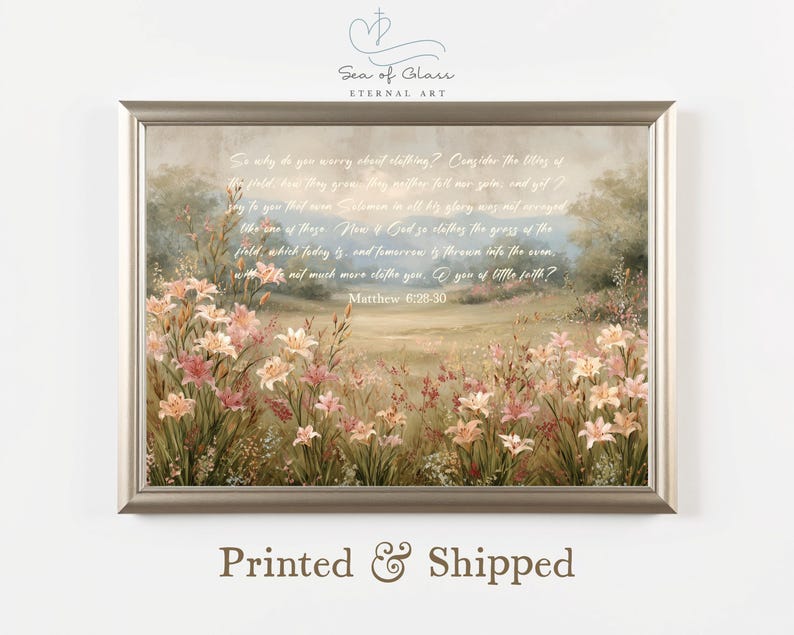 May include: A framed print featuring a pastoral scene with wildflowers and a quote from Matthew 6:28-30. The artwork has a soft, muted color palette with text that reads "Printed & Shipped". The frame is a neutral color.