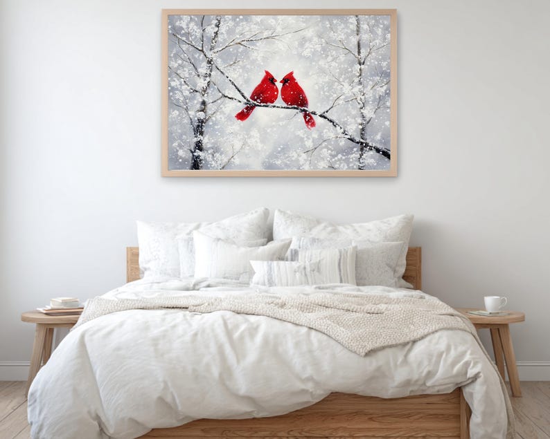 May include: A framed artwork depicts two red cardinals perched on a snow-covered branch. The painting has a winter theme with a soft, blurred background of snowy trees. The artwork is displayed above a bed with white bedding.