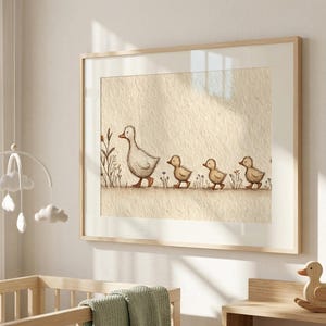 May include: A framed watercolor print depicts a mother duck and her three ducklings walking in a line. The artwork is in soft, neutral tones, with a beige background and a light wooden frame. The style is simple and suitable for a nursery.