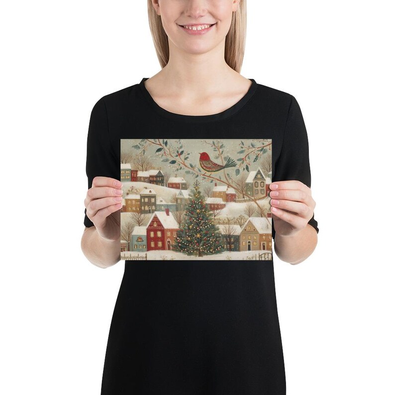 May include: A rectangular print featuring a winter village scene with snow-covered houses, a central decorated Christmas tree, and a red bird perched on a branch above. The illustration uses a muted colour palette of soft blues, reds, and browns.