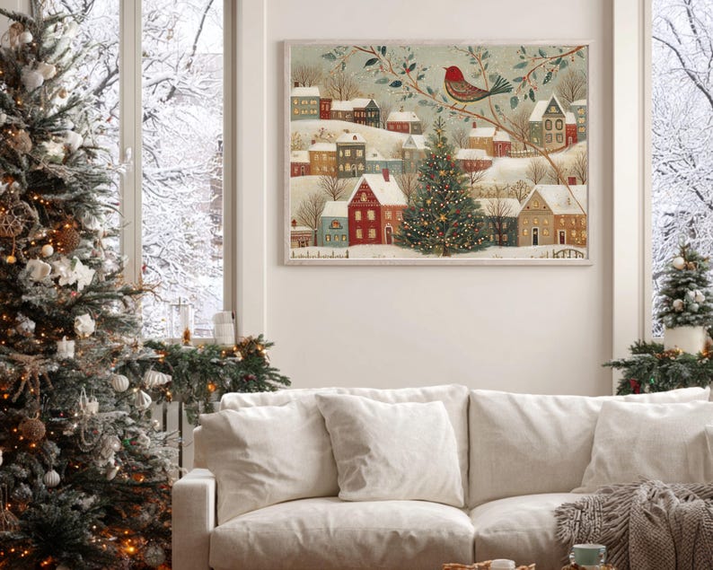 May include: A rectangular wall art print featuring a winter village scene with snow-covered houses, a central decorated Christmas tree, and a red bird perched on a branch. The illustration uses a muted colour palette of red, green, and white.