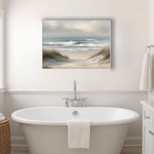 May include: A rectangular canvas print of a beach scene with a pathway leading to the ocean. The artwork features a neutral color palette with shades of beige, gray, and blue. The painting is displayed above a white bathtub in a bathroom.