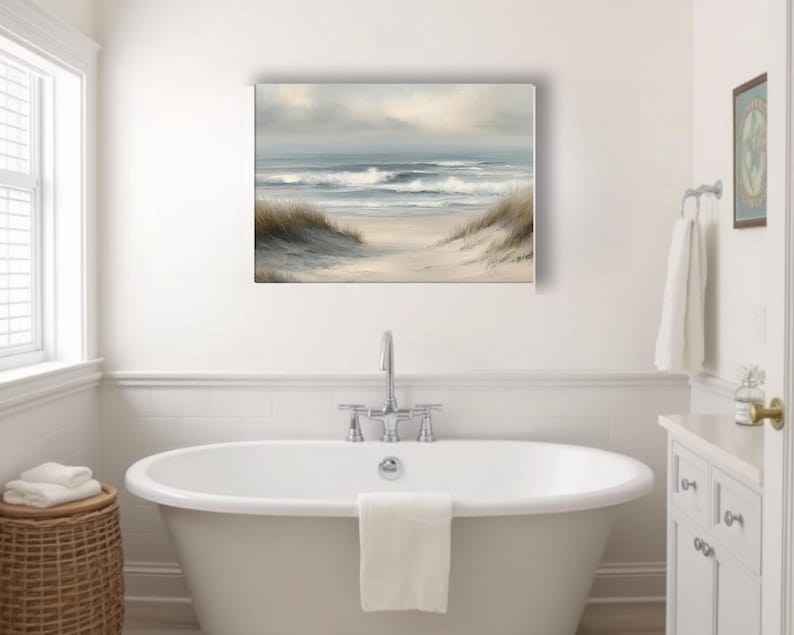 May include: A rectangular canvas print of a beach scene with a pathway leading to the ocean. The artwork features a neutral color palette with shades of beige, gray, and blue. The painting is displayed above a white bathtub in a bathroom.
