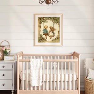 May include: A framed print of two children on a swing hangs above a light wood crib. The room features a white shiplap wall, a small nightstand with a floral arrangement, and a woven basket with pillows.