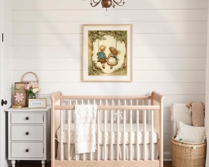 May include: A framed print of two children on a swing hangs above a light wood crib. The room features a white shiplap wall, a small nightstand with a floral arrangement, and a woven basket with pillows.