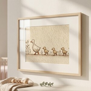 May include: A framed print featuring a watercolor illustration of a mother duck and her three ducklings walking in a line. The artwork has a neutral color palette with beige and brown tones, and is framed in a light wood frame.