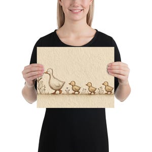 May include: A framed print featuring a mother duck leading three ducklings. The illustration is in soft, muted tones with a beige background and delicate floral accents. The ducks are depicted in a simple, charming style, evoking a sense of warmth and family.