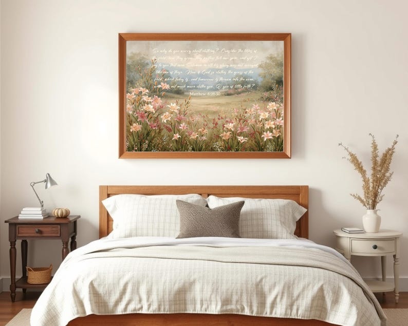 May include: A framed artwork featuring a pastoral scene with pink and white flowers in a field. The artwork has a wooden frame and includes text from Matthew 6:28-30. The artwork is displayed above a bed with a wooden headboard.