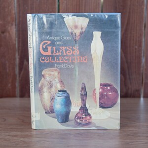 May include: A book titled "Antique Glass and Glass Collecting" by Frank Davis. The cover features a still life of various glass objects, including a vase, a bowl, and a bottle.