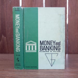 May include: A green and white hardcover book titled "Money and Banking" by Eugene S. Klise. The book is the third edition and features a stylized image of a building on the cover.