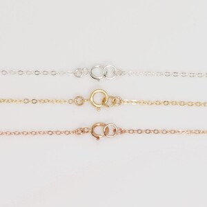 May include: Three delicate chains with lobster clasps. The chains are silver, gold, and rose gold.