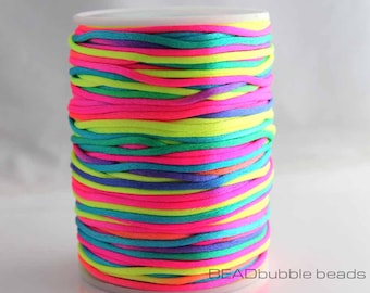 May include: A spool of neon coloured cord, wound tightly in a rainbow pattern. The cord is made of a soft, smooth material and is perfect for crafting.