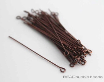 May include: A bundle of copper-colored head pins with a loop at one end. The head pins are arranged in a pile, with one pin extending out from the pile.