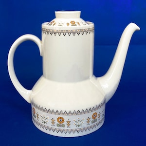 May include: White ceramic coffee pot with a floral pattern in shades of orange, green, and brown. The pot has a lid and a spout.