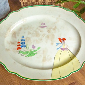 Art Deco oval serving platter with hand-painted lady in yellow crinoline dress, and flowers, 40.5cm long, 1930s