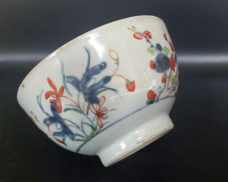 Puede incluir: Un cuenco de porcelana blanca con un dise&ntilde;o floral azul y rojo. El cuenco tiene un borde ligeramente acampanado y una base redondeada.
