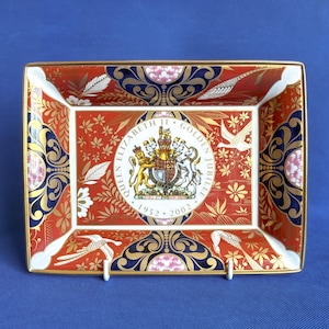 May include: A red and gold ceramic dish with a royal crest and the text "Queen Elizabeth II Golden Jubilee 1952 - 2002".