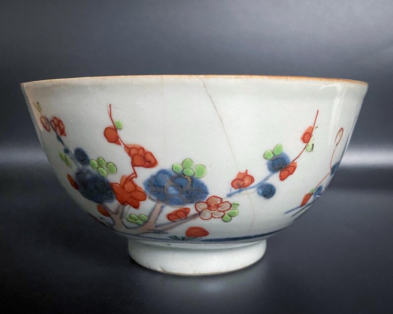 Puede incluir: Un cuenco de porcelana blanca con un dise&ntilde;o floral en azul, rojo y verde. El cuenco tiene un borde ligeramente acampanado y una base redondeada.