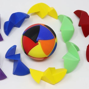 以下が含まれることがあります： 12個のピースからなるカラフルなパズルボール。各ピースは異なる色と形をしています。ピースはボールの周りに円形に配置され、ボールは画像の中央にあります。